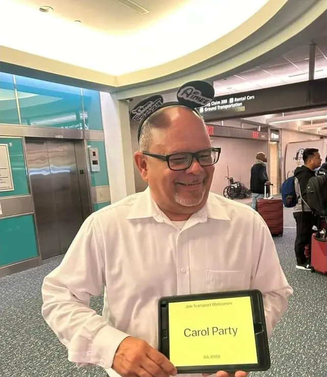 Pedro at Orlando International Airport holding a tablet sign with his riders' party name